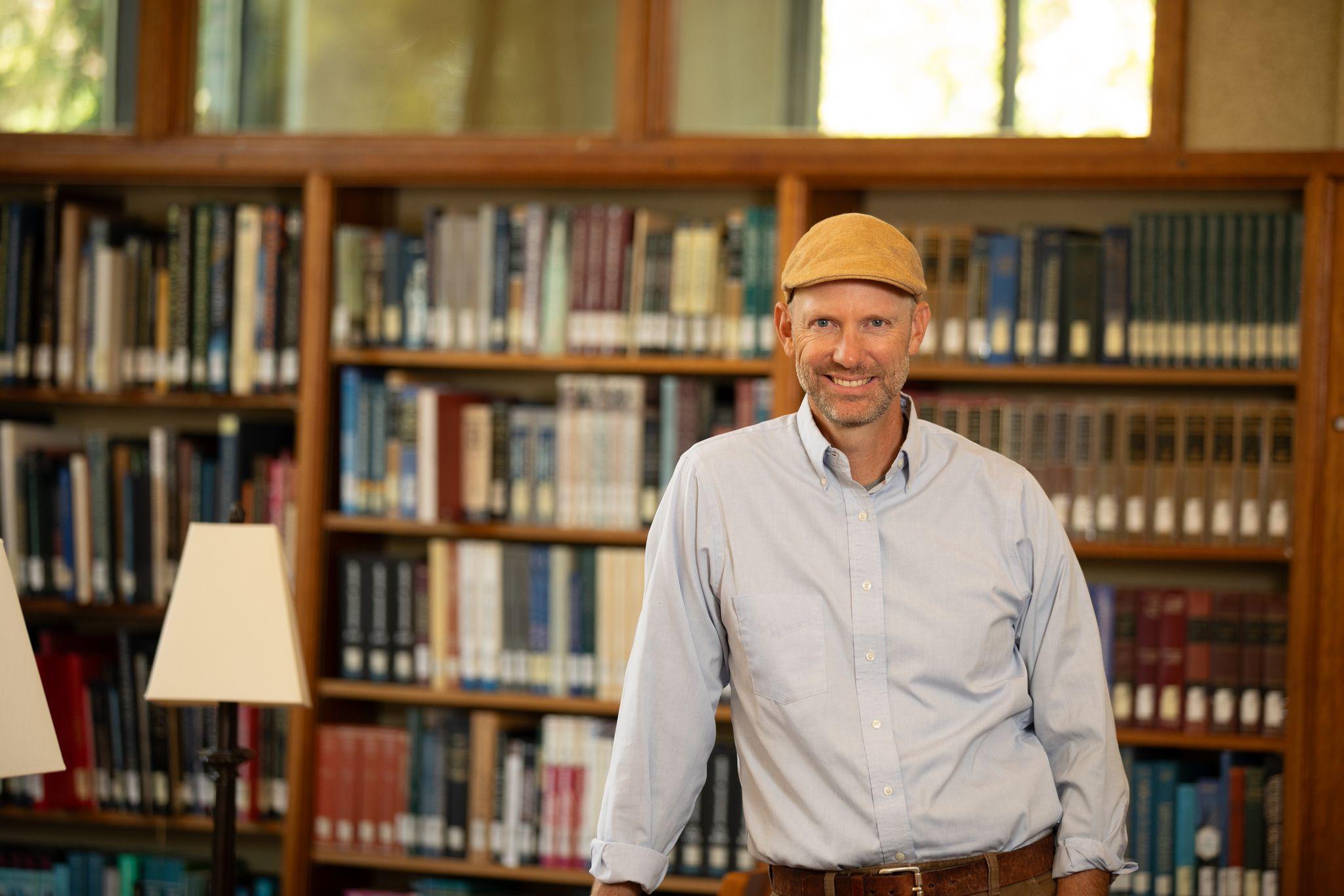 Greg Dodds poses in front of book shelves in the library.